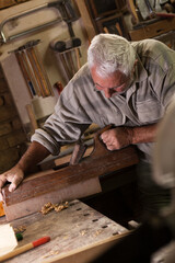Experienced carpenter working in his workshop.Working with hand wood planer.