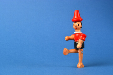 Wooden puppet depicting Pinocchio walking on a blue background