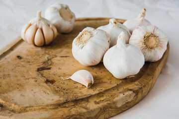 White garlic bulbs on wooden board, on light background. Natural antibiotic. Kitchen and cooking.
