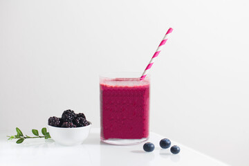 Berry smoothie in a glass with a straw and blueberries and blackberries. Detox, healthy eating.