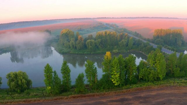 4k drone flight moving to the side footage (Ultra High Definition). Superb summer sunrise on Ternopil outskirts with two lakes and asphalt road on the midle. Morning view of field of wheat.