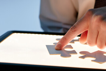 man with a graphic tablet is collecting a puzzle while sitting at his desk .