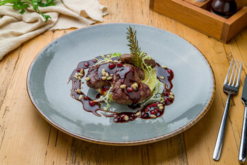 fried deer fillet with berry sauce on grey plate on wooden table