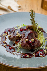fried deer fillet with berry sauce on grey plate on wooden table