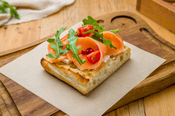 Bruschetta with salmon, cheese, aragula and cranberries on wooden board