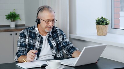 A man wearing headphones participates in online negotiations on a laptop.