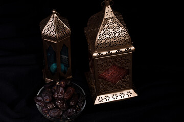 Ramadan concept. Dates close-up in the foreground. Ramadan Lantern on a wooden table. wall background. Space for text on the right. iftar concept image.