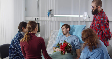 Young people visiting friend in hospital and bringing flowers