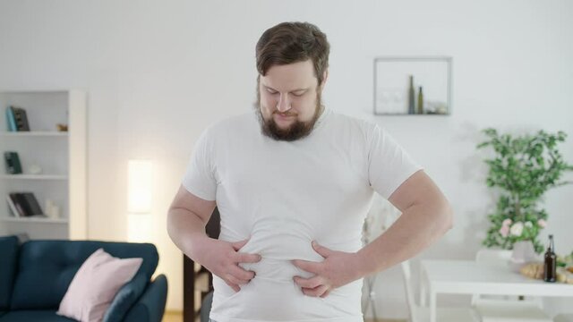 Depressed overweight man touching belly fat, physical inactivity, insecurities