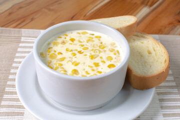 Corn flakes with gratin cheese, accompanied by bread on wooden background