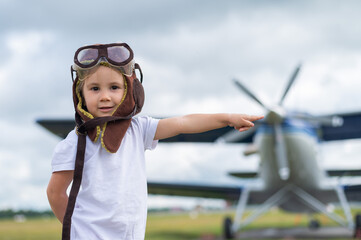 A cute little girl dressed in a cap and glasses of a pilot on the background of an airplane. The child dreams of becoming a pilot. © Михаил Решетников