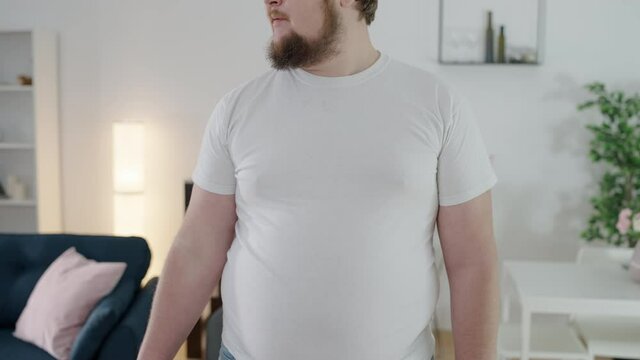 Upset oversize man looking at small T-shirt, weight loss problem, appearance