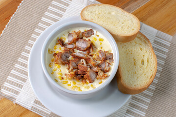 Corn flakes with gratin cheese, fried bacon accompanied by bread on wooden background