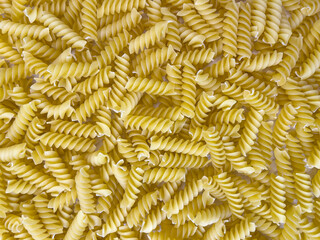 Food background or texture raw dry Italian pasta in shape of spiral. Closeup, macro, top view. Uncooked macaroni