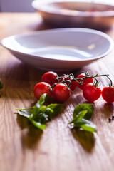 Cherry Tomatoes Mint Garlic and Eggplant Prepared to bee cooked. White plate. Vegetables on the wooden table. Fresh Cheery Tomato. Raw vegetables. Beautifull Light Photography. Macro. Close Up.