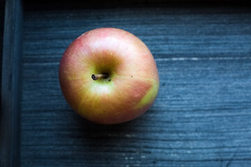Top view to round red and green ripe cortland apple on grey wooden background. Isolated round fruit. Raw vegetarian food. Vitamines and health care in isolation concept. Copy space. 