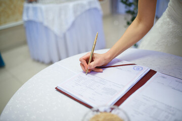 bride putting signature in wedding document