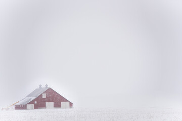 red barn in snow and fog