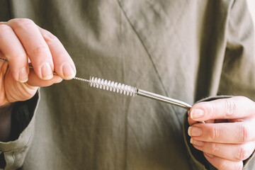 A woman cleans metal straws with a special brush. Environmental product, plastic replacement, absolutely safe clean environment. Eco-friendly, no waste