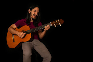 Obraz premium Man smiling and playing guitar with black background