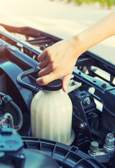 Check auto car's coolant level. That service, repair or maintenance by women hand to open cap of tank or reservoir for filling liquid cooled engine with water, antifreeze in radiator, cooling system.