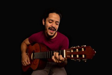 Obraz premium Man playing guitar and singing with black background