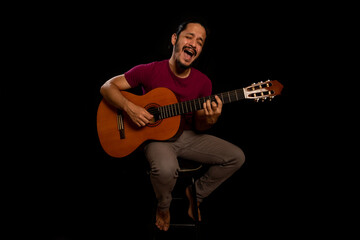 Man playing guitar and singing with black background