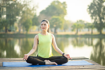 Young woman practicing yoga, breathing, meditation in lotus pose on a yoga mat
