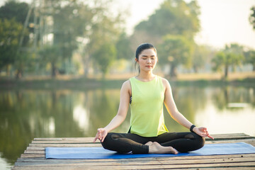 Young woman practicing yoga, breathing, meditation in lotus pose on a yoga mat