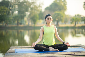 Fototapeta na wymiar Young woman practicing yoga, breathing, meditation in lotus pose on a yoga mat