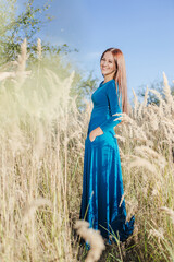 Obraz premium Beautiful girl in a blue dress on a background of nature