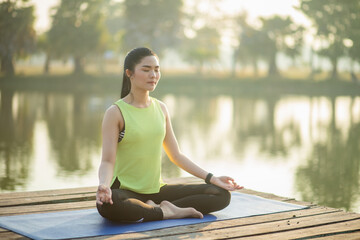 Young woman practicing yoga, breathing, meditation in lotus pose on a yoga mat
