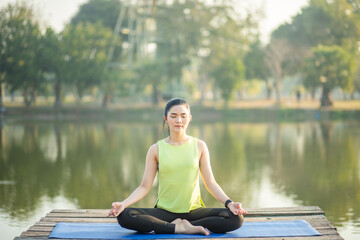 Fototapeta na wymiar Young woman practicing yoga, breathing, meditation in lotus pose on a yoga mat