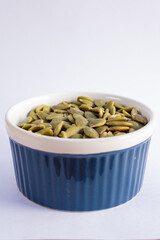 Roasted pumpkin seeds on blue bowl isolated