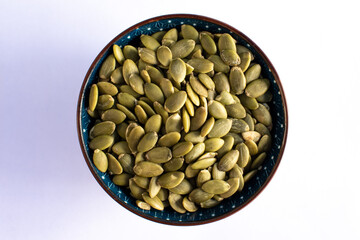 Roasted pumpkin seeds on blue bowl isolated