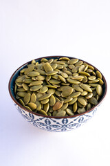 Roasted pumpkin seeds on blue bowl isolated