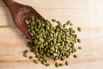 Roasted pumpkin seeds in a wooden spoon on wooden background