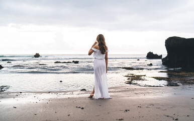 Anonymous woman standing near waving sea