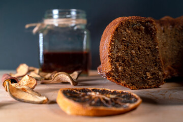 Still life with homemade cake, jar with honey and dipper, cinnamon, dried fruits, star anise on a wooden board. Small healthy snacks to enjoy during coffee break.