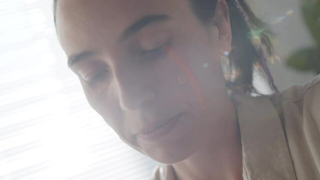 Dutch angle tilt down shot of young Caucasian woman weaving macrame decoration at home