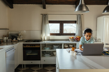 Black boy with earphones having online class at home