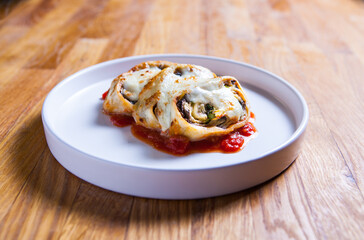 Roulade with eggplant, onion and basil in tomato sauce covered with motzarela. Italian cuisine dish.