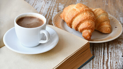 Сup of coffee and croissant on a wooden table