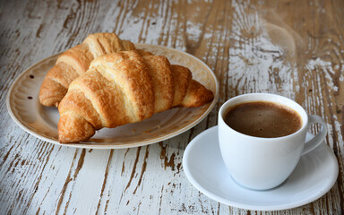 Сup of coffee and croissant on a wooden table