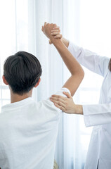 Obraz premium Female doctor doing physical therapy By extending the shoulder of a male patient