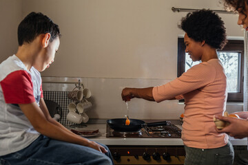 Black woman baking egg while her son sitting near her