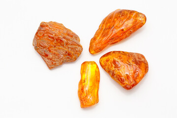 Four different transparent polished yellow amber pieces on a white background. Sun stone. Natural mineral material for jewelry. Amber texture. Copal. Multicolored yellow background. Ancient  resin