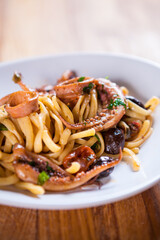 Pasta with calamari seasoned with red cherry olives and basil. Calamari spaghetti on white plate. Mediterranean pasta. seafood. Italian food. Fine dish. Fres food