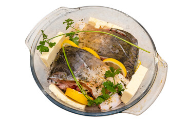 Pieces of raw carp arranged in a glass bowl with butter, parsley and lemon slices, isolated on a white background with a clipping path, top view.