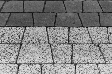 Surface of the paving stone. Black and white marble chips and matt black color. The shape of the stones is in the form of a trapezoid. Angle view, perspective.